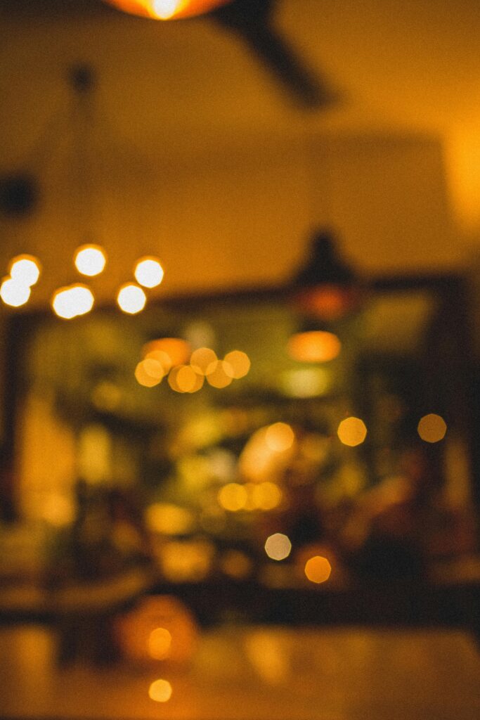 Defocused view of warm ambient lighting in a cozy café interior, perfect for a relaxing evening atmosphere.
